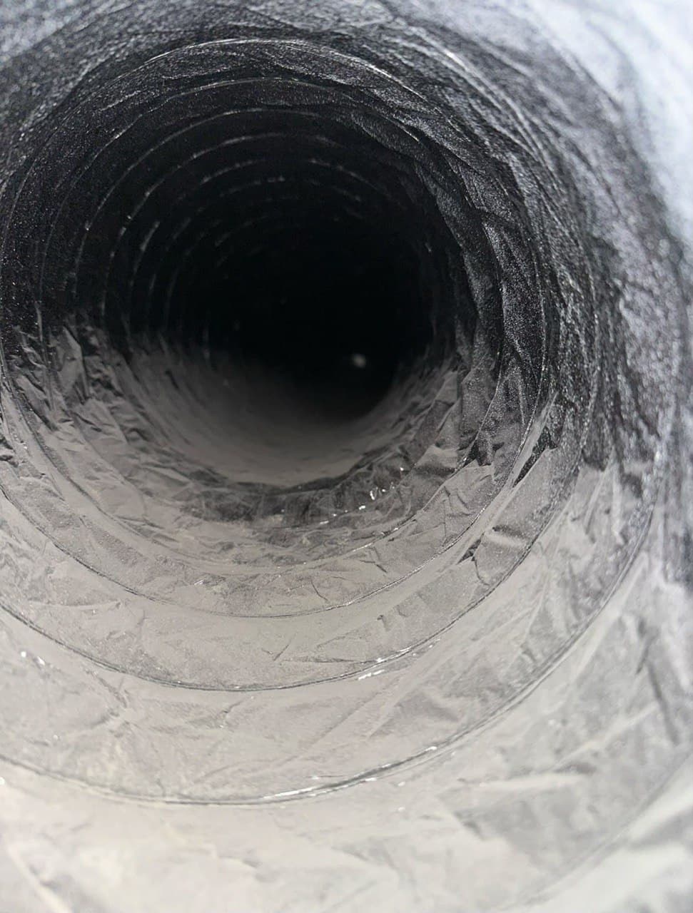 Close camera view showing dust and material inside flexible residential ductwork